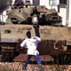 A Palestinian youth hurls a rock at an Israeli tank.